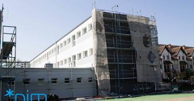 Galeria zdjęć przedstawia budynek szkoły, w którym prowadzone są prace termomodernizacyjne. Widać na nim m.in. rusztowania.