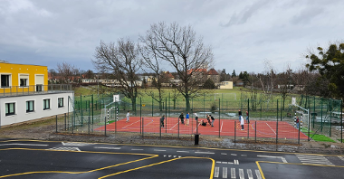 Zdjęcie przedstawia boisko, na którym uczniowie grają w piłkę.