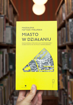 okładka książki na tle bibliotecznych regałów
