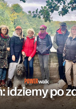 Grupa ludzi stoi przy murku obok jeziora Rusałka. Przed nimi napis o treści Poznań idziemy po zdrowie.