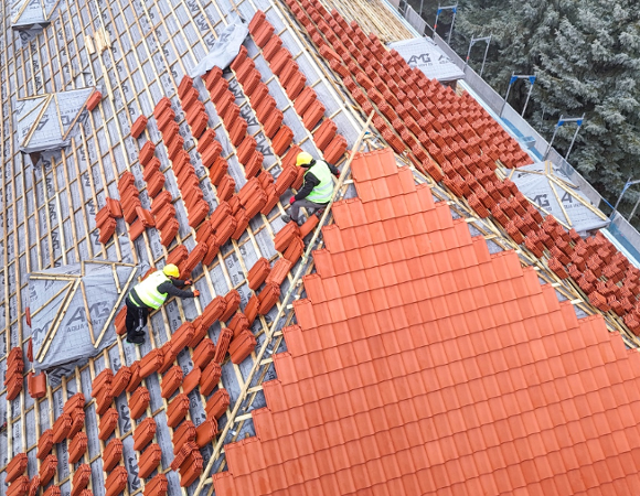 Układanie nowej dachówki na dachu przedszkola