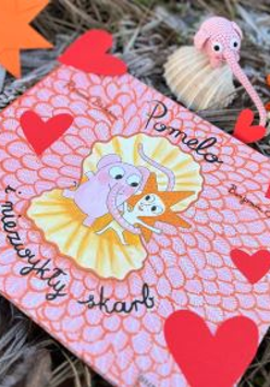 Okładka książki o słoniu Pomelo. W centralnej części słoń i jego przyjaciel, dookoła czerwone serduszka. Napis: Pomelo i niezwykły skarb.