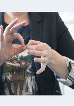 Dłonie kobiety, które pokazują jeden ze znaków w polskim języku migowym