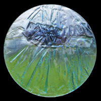 Na zdjęciu na czarnym tle okrąg ze szkła w dolnej części zielonkawy w górnej niebieski.