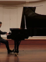 Na zdjęciu mężczyzna siedzący przy fortepianie.