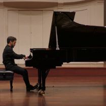 Na zdjęciu mężczyzna siedzący przy fortepianie.