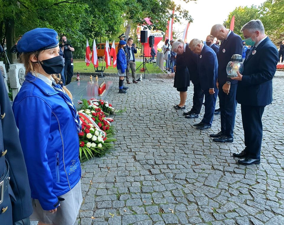 Cmentarz na Westerplatte. Po lewej pomnik, po prawej samorządowcy w uroczystym pokłonie, tuż po złożeniu kwiatów - grafika artykułu
