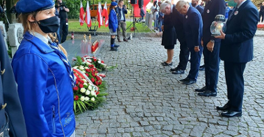 Cmentarz na Westerplatte. Po lewej pomnik, po prawej samorządowcy w uroczystym pokłonie, tuż po złożeniu kwiatów