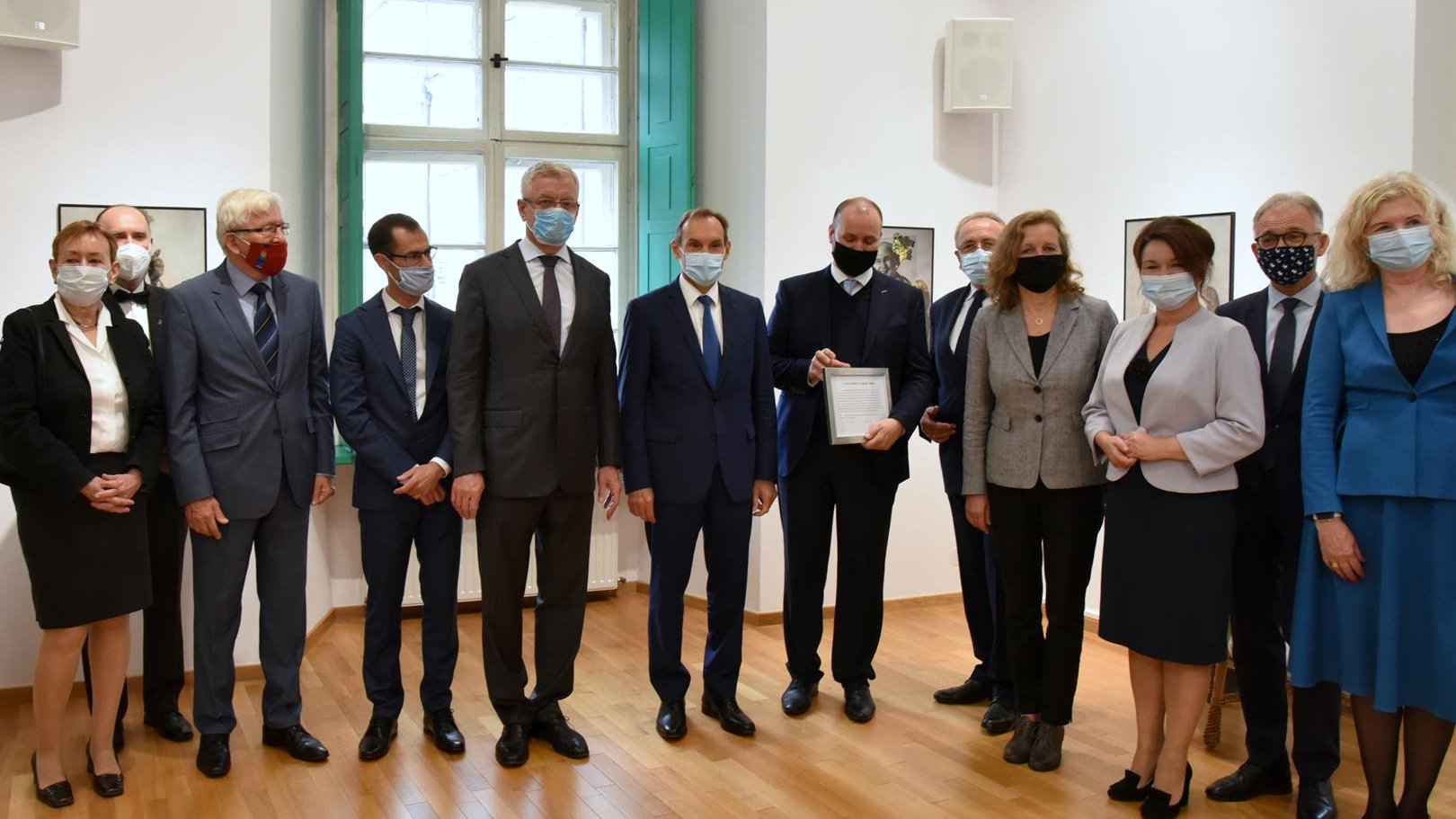 Grupa ludzi ustawiona do zdjęcia. W centrum ambasador Francji, Jacek Jaśkowiak - prezydent Poznania oraz nowy konsul honorowy