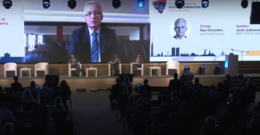 Kadr z relacji live: duża sala wypełniona ludźmi. Na scenie trzy osoby - prowadzący. Za nimi duży ekran, a a nim Jacek Jaśkowiak, prezydent Poznania