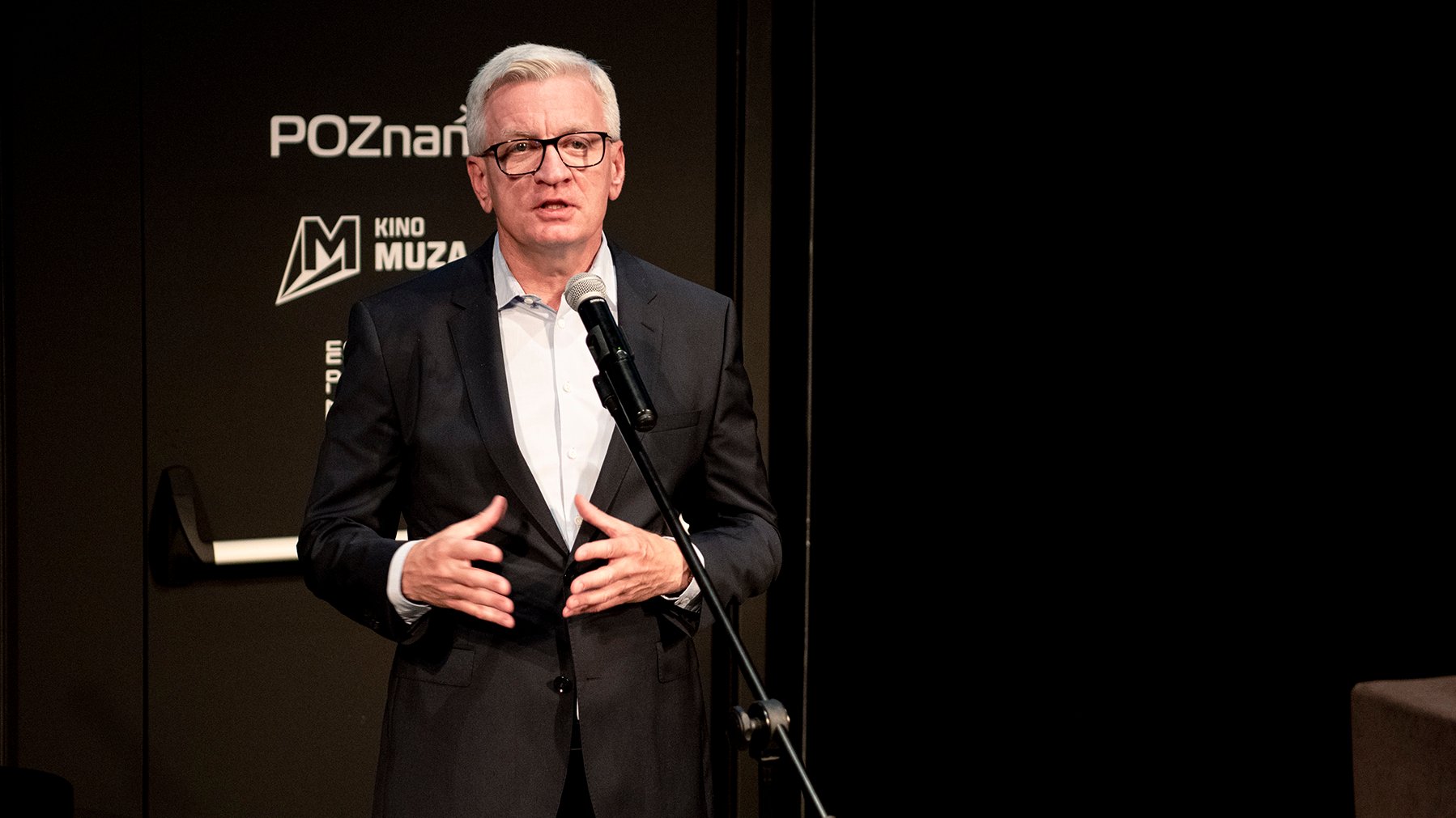 Na zdjęciu Jacek Jaśkowiak, prezydent miasta, stoi przy mikrofonie, w tle napisy: Poznań, Kino Muza - grafika artykułu