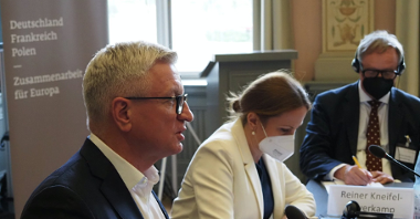 Na zdjęciu trzy osoby przy stole, na pierwszym planie Jacek Jaśkowiak, prezydent Poznania, widoczny z profilu