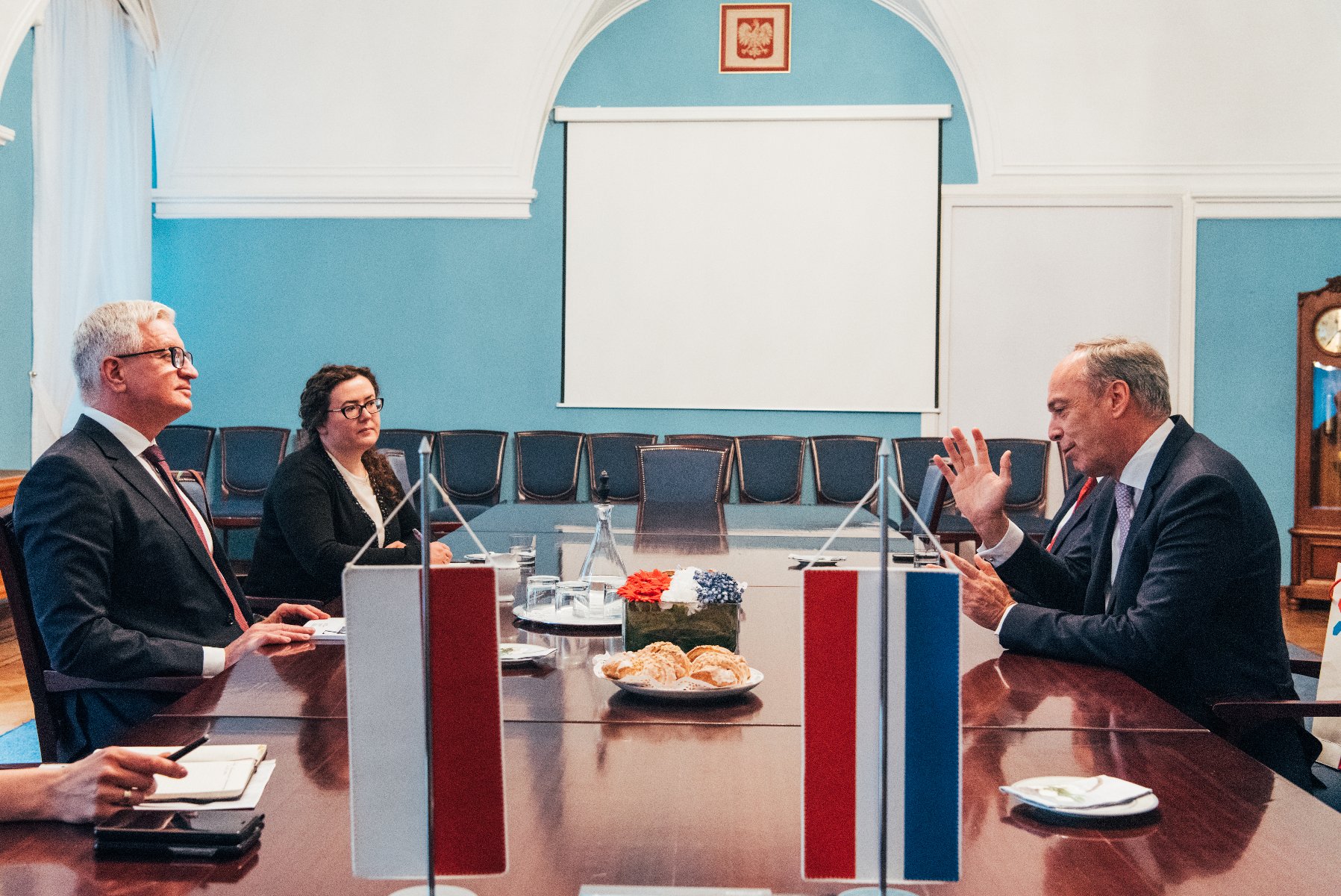 Na zdjęciu Jacek Jaśkowiak rozmawia z ambasadorem Luksemburga, siedzą przy dużym stole, gestykulują - grafika artykułu