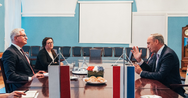 Na zdjęciu Jacek Jaśkowiak rozmawia z ambasadorem Luksemburga, siedzą przy dużym stole, gestykulują