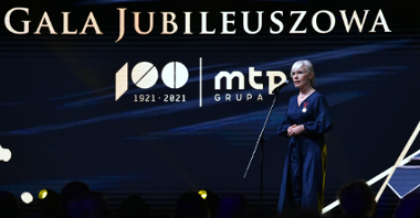 Na zdjęciu kobieta o jasnych włosach przy mikrofonie, w tle napis: gala jubileuszowa