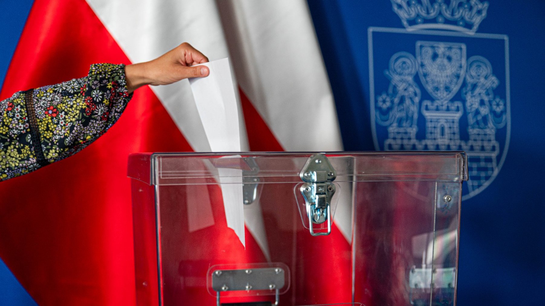 Na zdjęciu dłoń wrzucająca kartę do urny