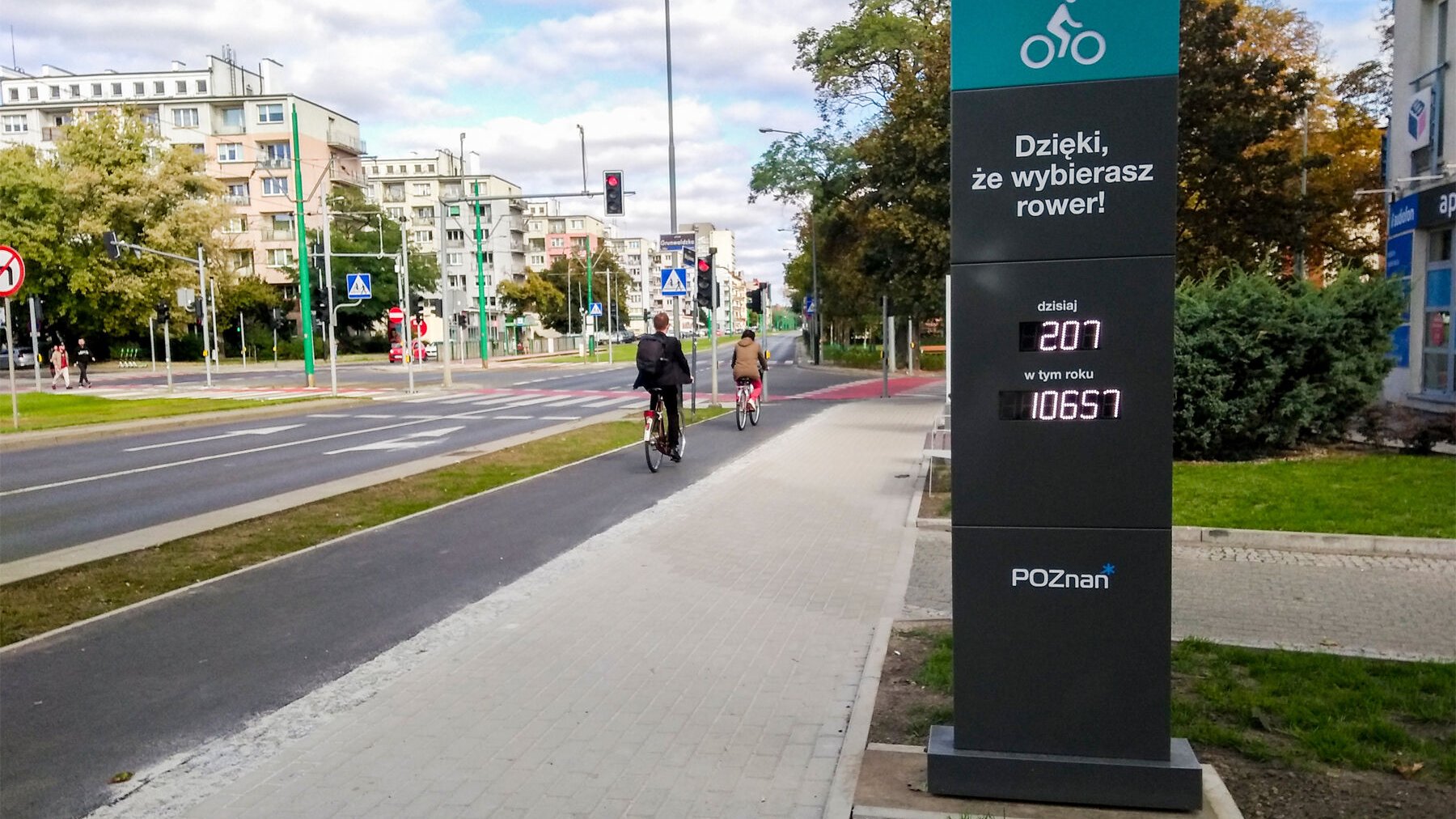 Licznik rowerowy przy ul. Grunwaldzkiej, na drodze rowerowej 2 rowery, po obu stronach bloki.