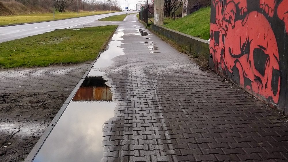 Droga rowerowa, po lewej czewrony mural.