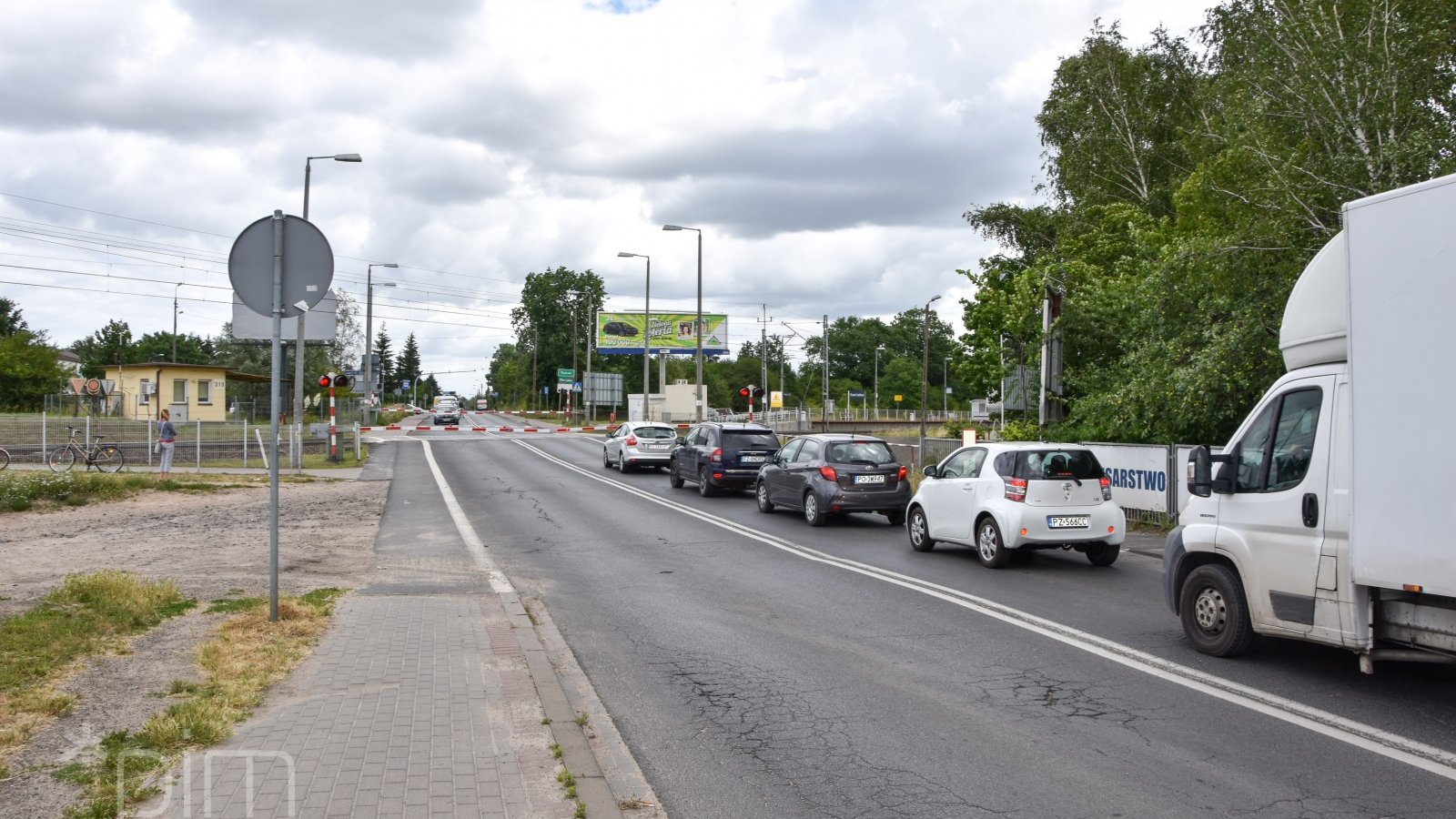 Ul. Grunwaldzka. Samochody oczekuja przed zamknietym przejazdem kolejowym.