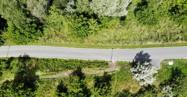 Droga rowerowa prowadząca przez tereny zielone widziana z góry.