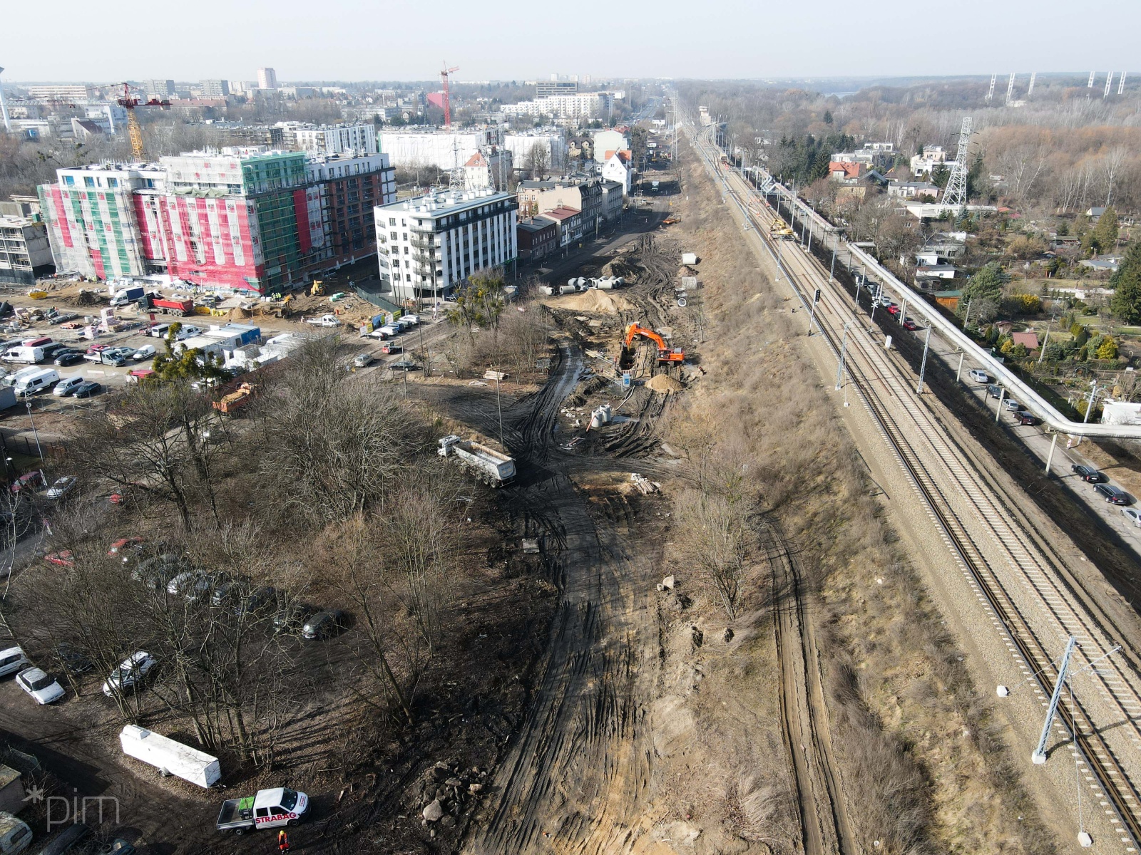 Widok z góry. Po prawej tory kolejowe, po lewej bloki i parkingi. Na dole plac budowy. - grafika artykułu