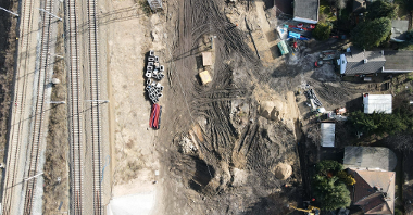 Widok z góry na plac budowy. Po lewej tory kolejowe, po prawej zabudowania