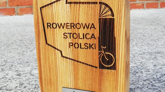Drewniana deseczka z logo Rowerowej Stolicy Polski, na dole deseczki metalowa tabliczka, na której napisano Poznań 2024.