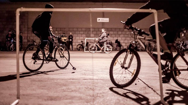 Osoby na rowerach graja w polo. Boisko z dwoma bramkami.