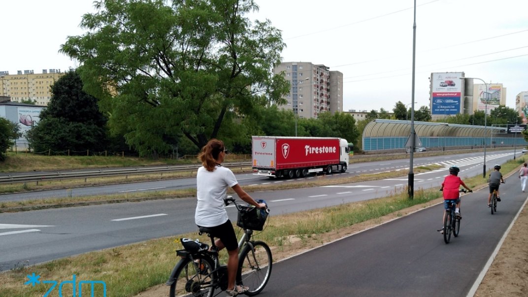 rowerzysci i piesi na wyremontowanej trasie, dalej tir i drzewo