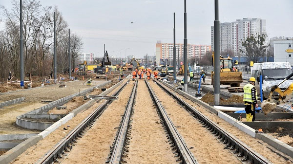 Tory tramwajowe w budowie. W głebi pracownicy budowlani i maszyny.