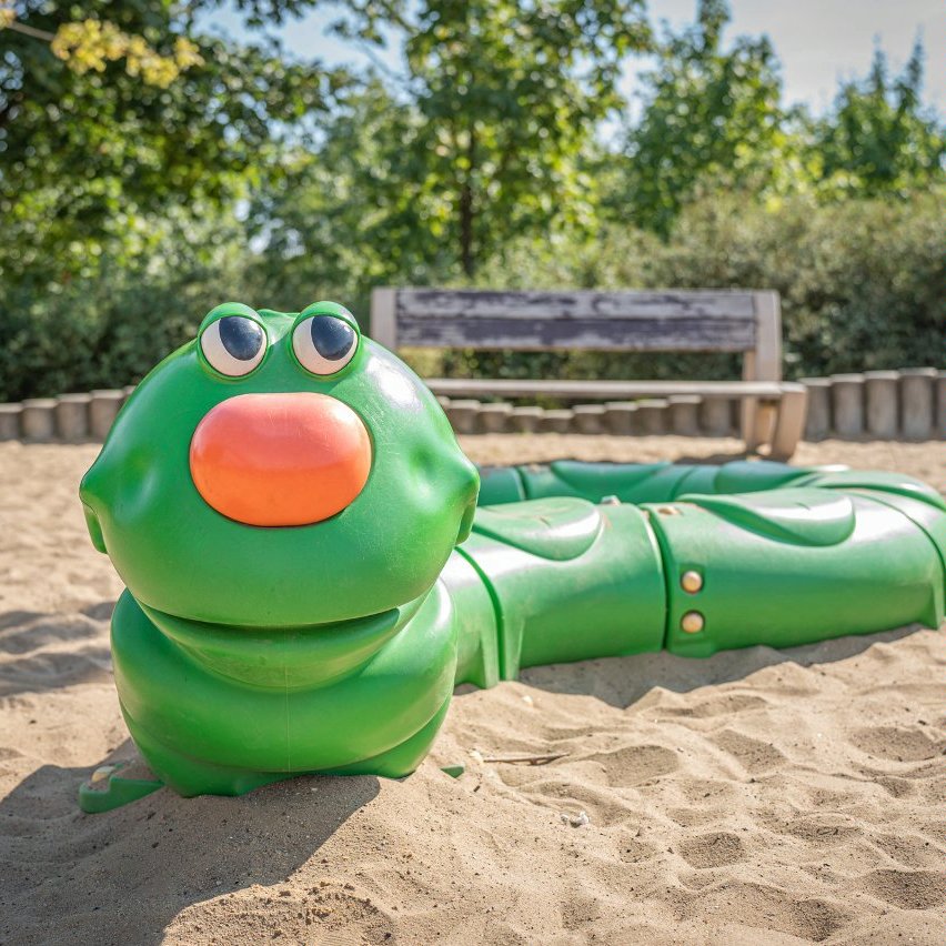 Plastikowa zielona gąsienica z pomarańczowym nosem do zabawy dla dzieci "wijąca się" po piasku.