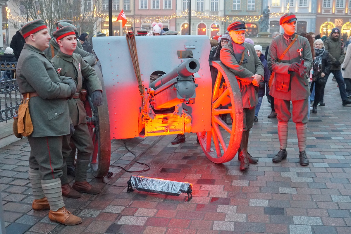 Four men in insurgent costumes stand next to a cannon.