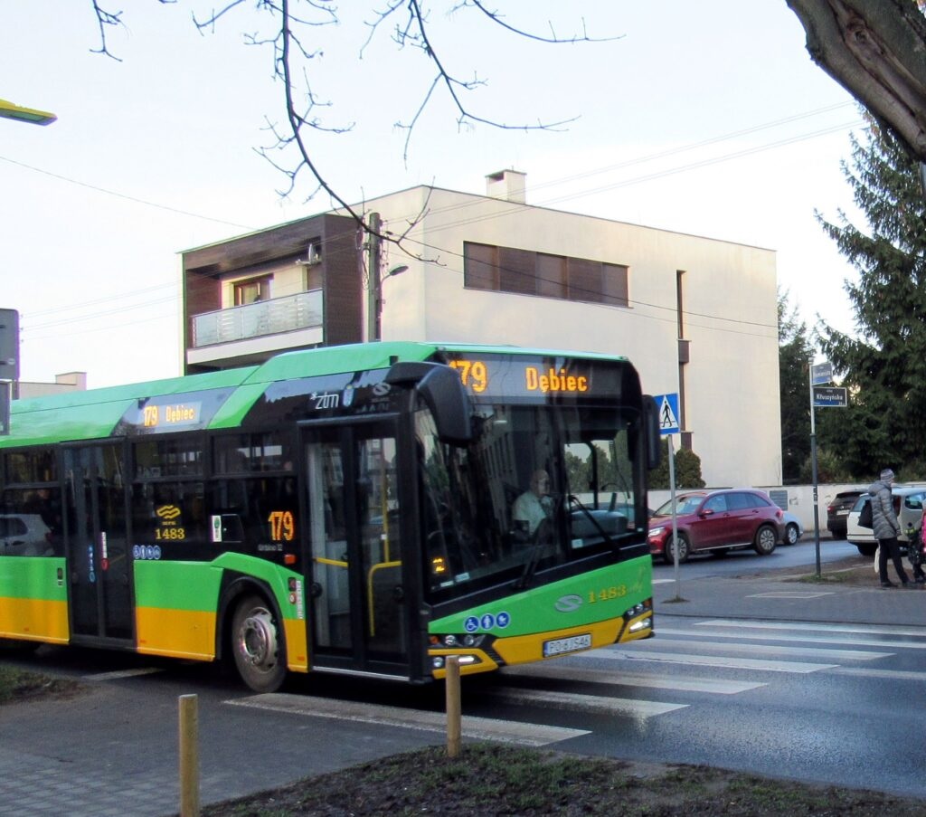 Fot. ZTM Poznań autobus linii 179 przed przejściem dla pieszych, za nim widoczny budynek i samochody