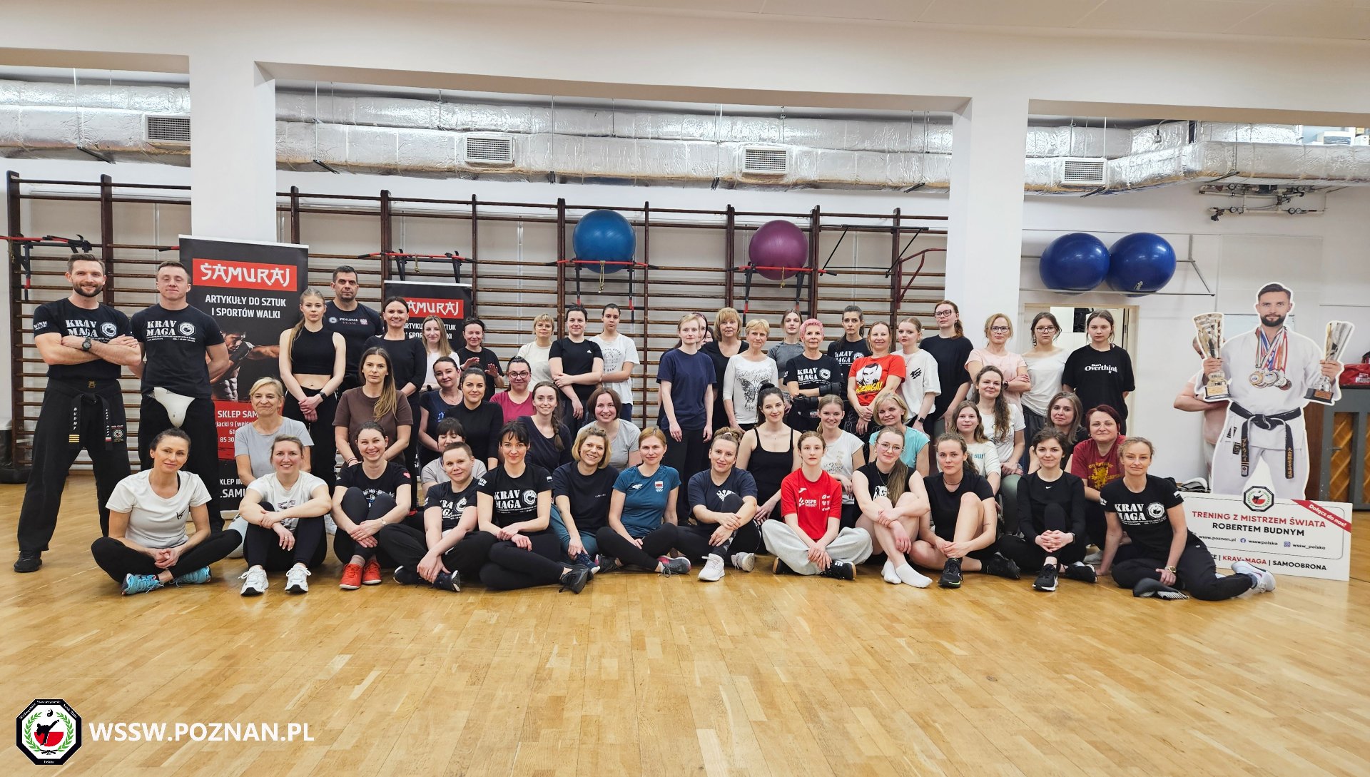 Bezpłatny kurs samobrony dla kobiet - na wspólnym zdjęciu kilkadziesiąt kobiet w sali sportowej wraz z kadrą instruktorów