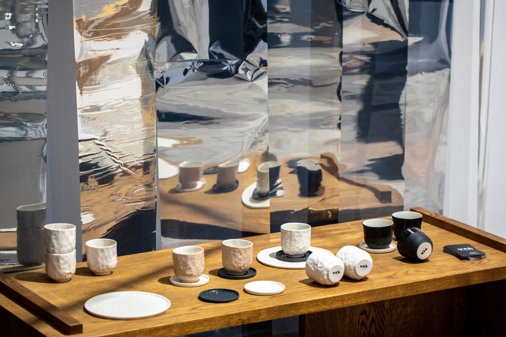 Ceramiczne naczynie są w spokojnych kolorach - białym, kremowym i czarnym, niektóre z nich stoję, inne leżą.