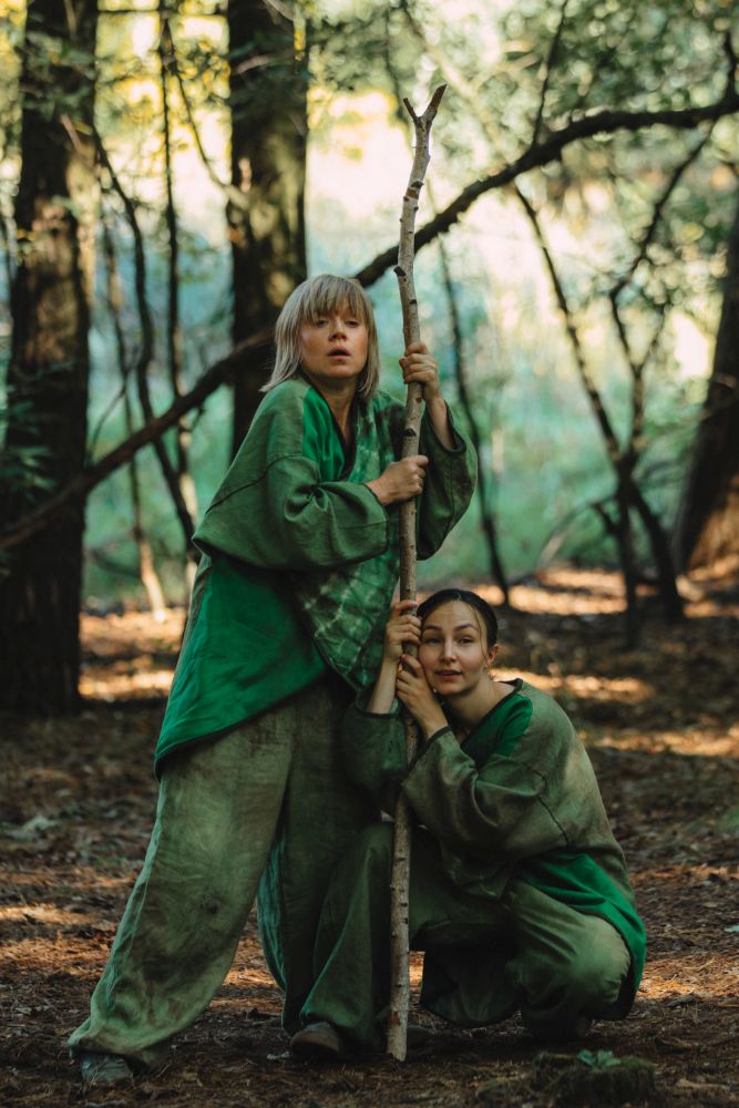 Dwie kobiety w zielonych strojach w lesie.