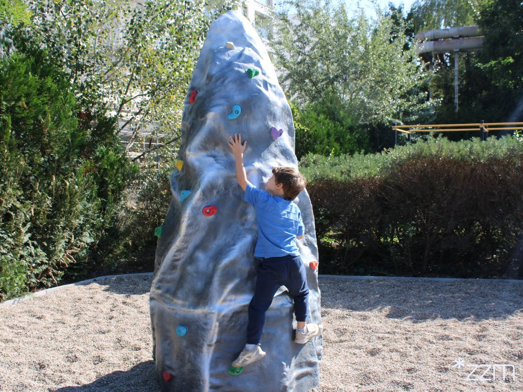 Dziecko trzymające się ścianki wspinaczkowej.
