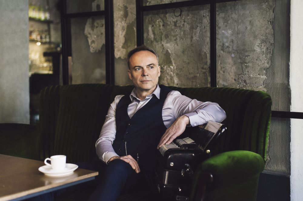 Elegancki mężczyzna z akordeonem siedzi w kawiarni.