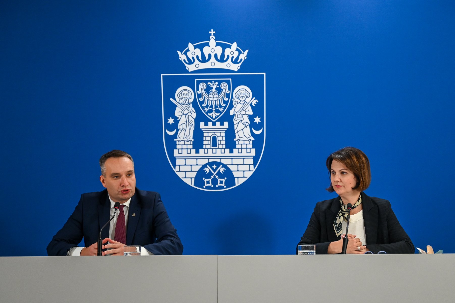 Grafika z konferencji. Przedstawia dwie osoby - dyrektor WDGIR Joanna Jajus i wiceprezydenta miasta Poznania Mariusz Wiśniewski.