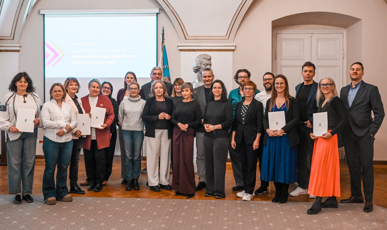 grupa kilkunastu osób kobiet i mężczyzn pozuje do zdjęcia w sali