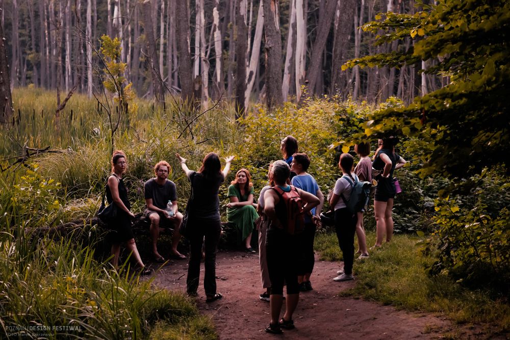 Grupa ludzi w kręgu stoi w lesie.