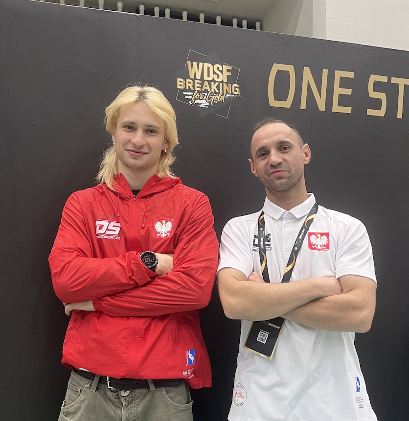 Grzegorz Smoczyk i trener Radosław Arent - 2 mężczyzn w strojach reprezentacji Polski stoi na tle ścianki zawodów