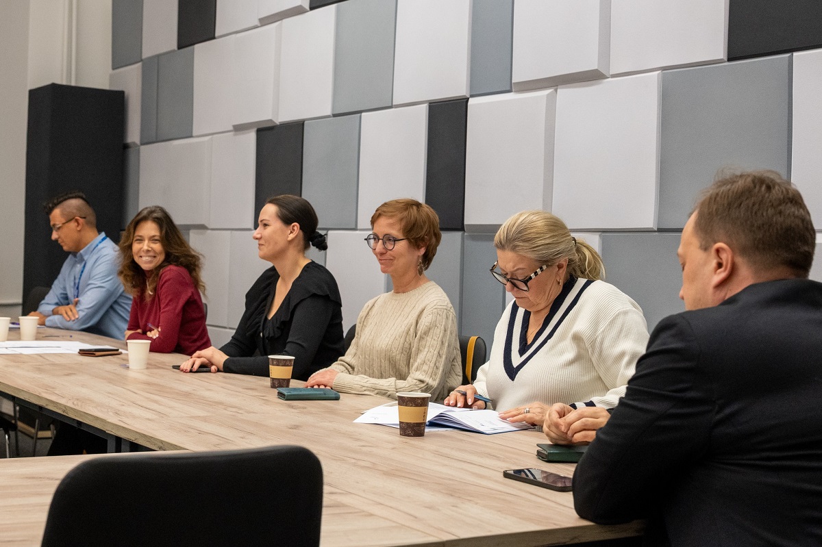 kilkoro osób siedzi w sali przy stole konferencyjnym - grafika artykułu