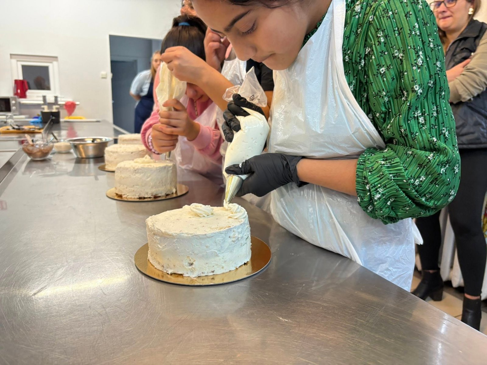 Kobieta w kuchni dekoruje ciasto, otoczona przyborami do pieczenia.