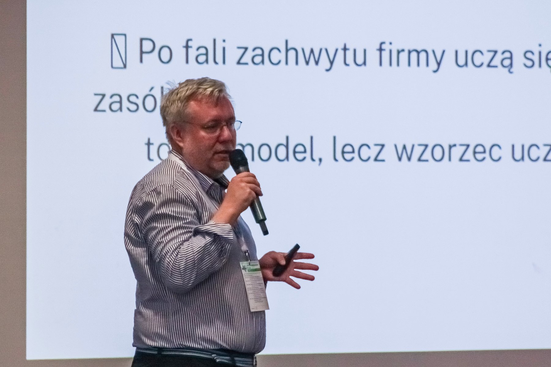 mężczyzna na tle ekranu, na którym wyświetlana jest prezentacja dotycząca sztucznej inteligencji