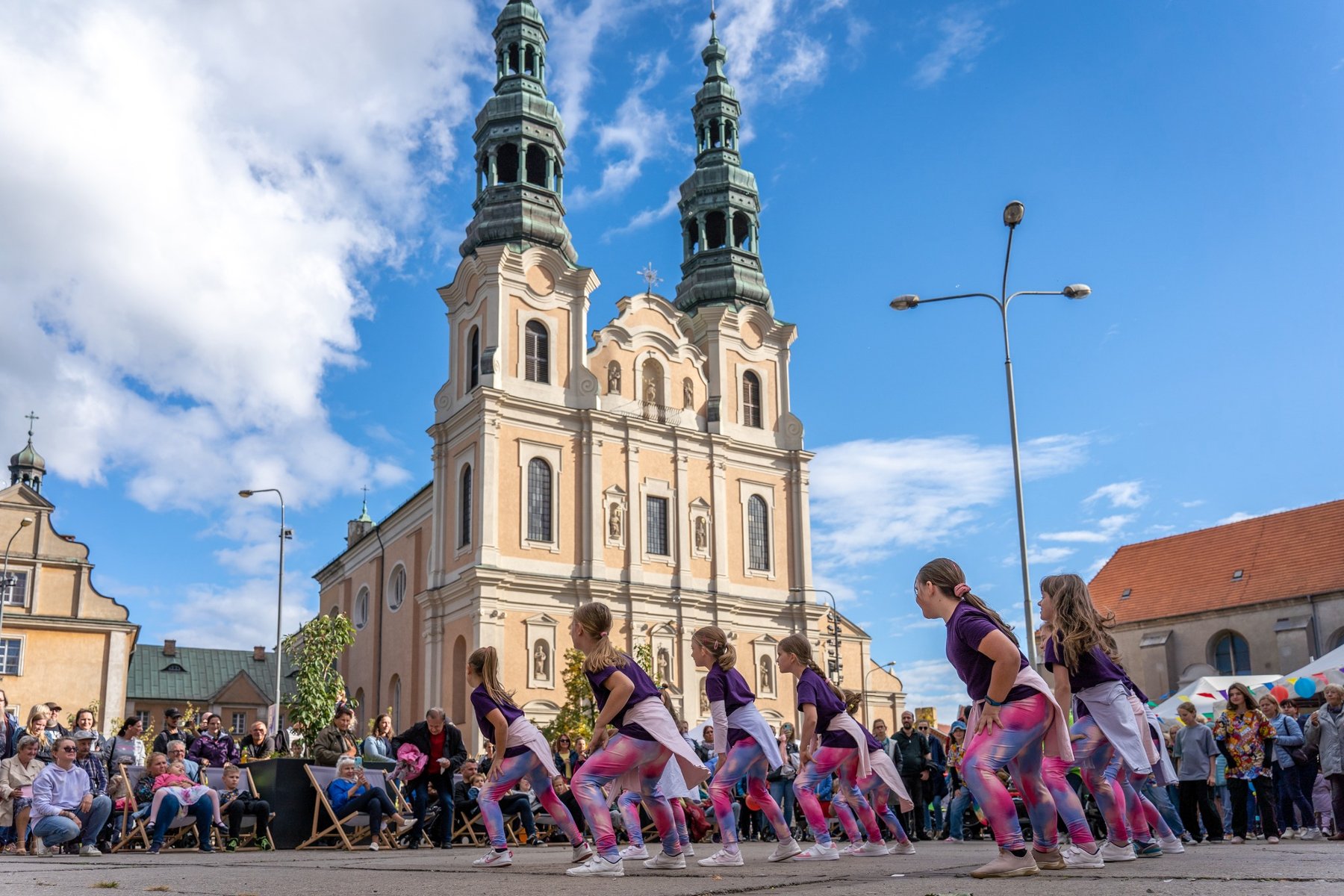 Prognoza pogody na weekend zapowiada się wyjątkwo letnie, dlatego warto wziąć udział w Święcie, fot. Paweł Liszkowski Mężczyzna w przebraniu zieje ogniem. Za nim idzie korowód i kobiety na szczudłach. W tle kamienice.