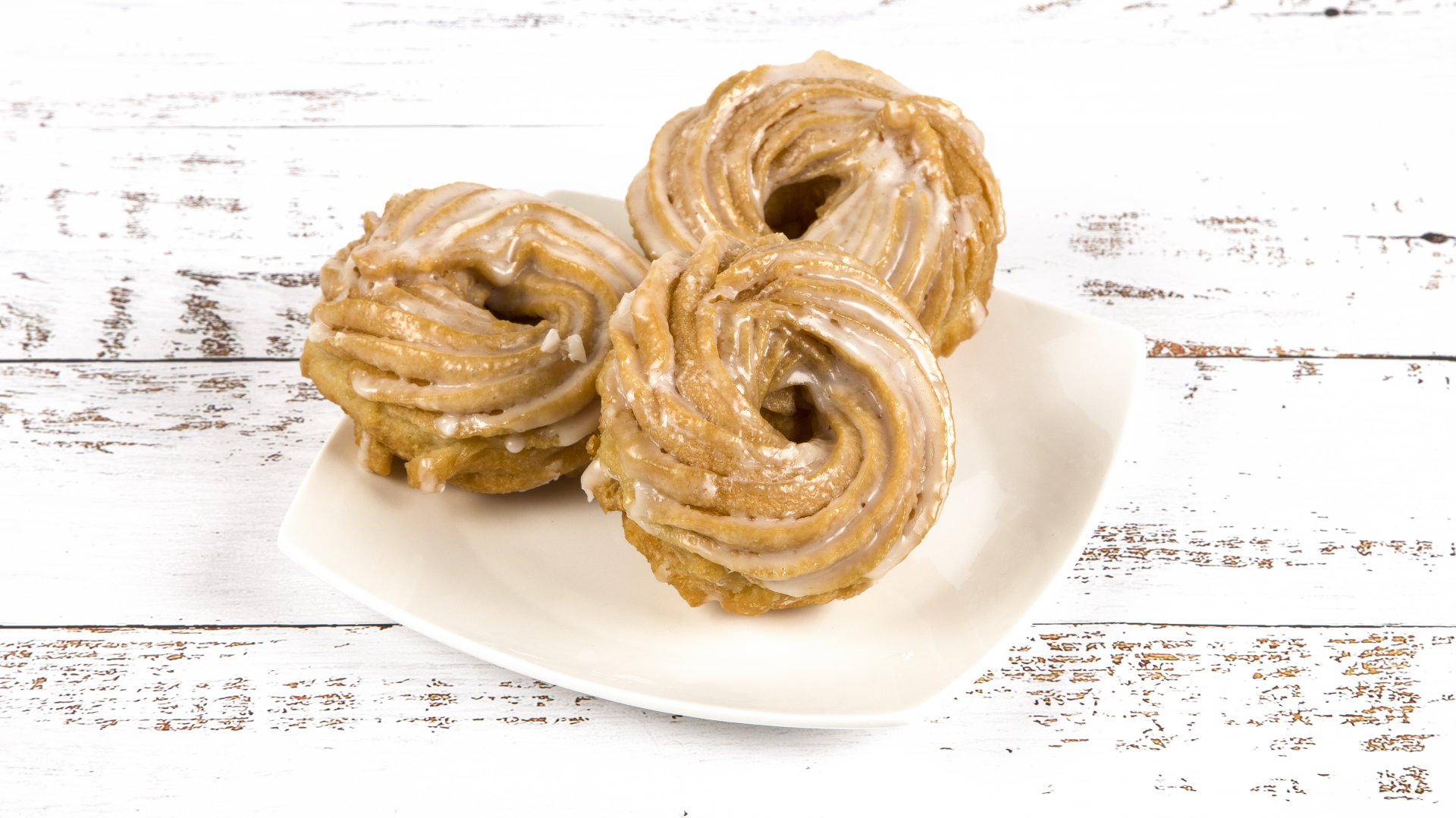 Na białym talerzu trzy ciastka - gniazdka poznańskie.