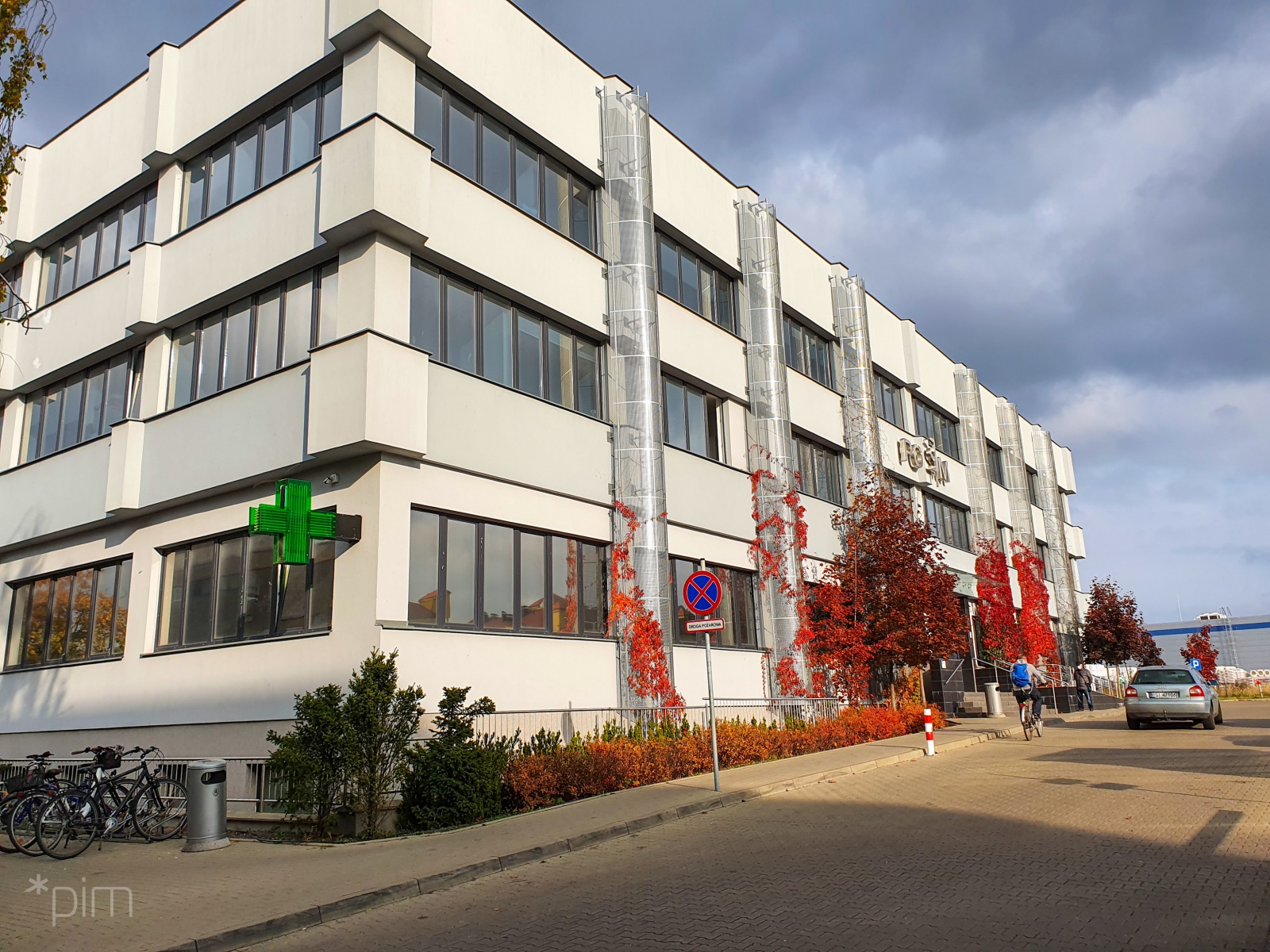 Na zdjęciu budynek POSUM, widać jego fasadę, przed nią człowiek na rowerze