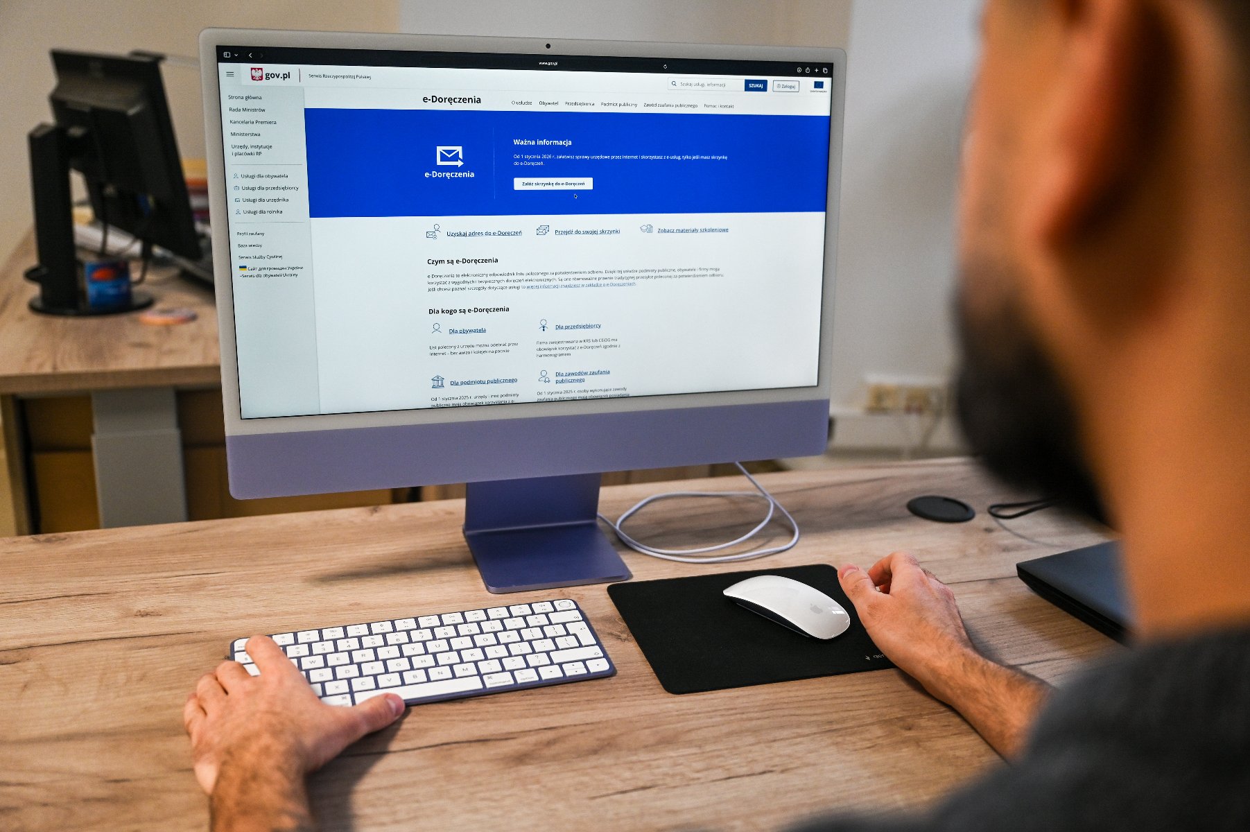 Na zdjęciu człowiek siedzący przed komputerem, na ekranie widać stronę e-Doręczeń- zbliżenie