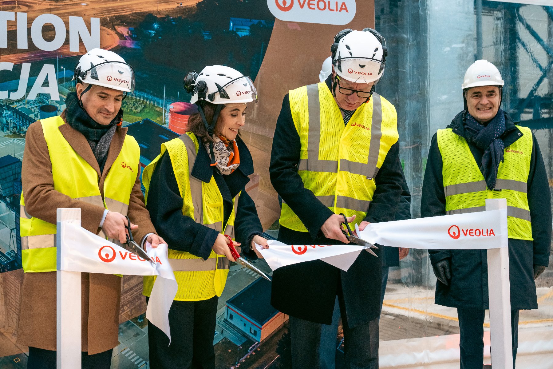 Na zdjęciu cztery osoby w kamizelkach i kaskach ochronnych przecinają wstęgę z napisem: Veolia